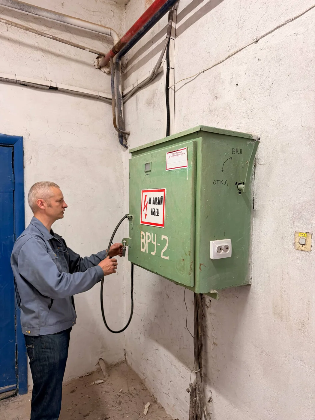 Инженер SmartEnergy с прибором у распределительного щита во время планового обслуживания